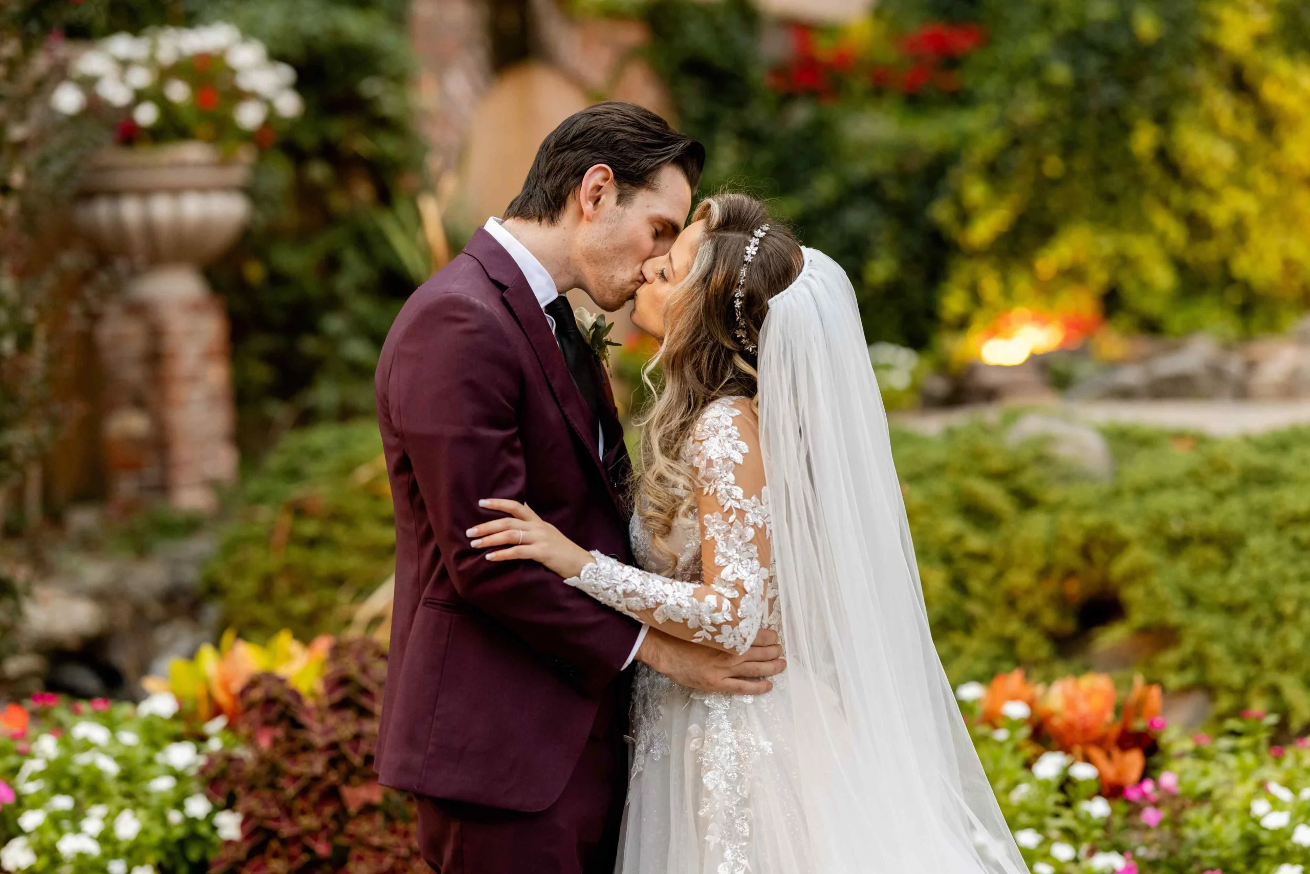 Bride and groom sharing a kiss in the garden surrounded by fall foliage on their wedding day